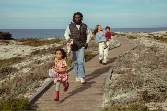 The family running along a boardwalk by the ocean